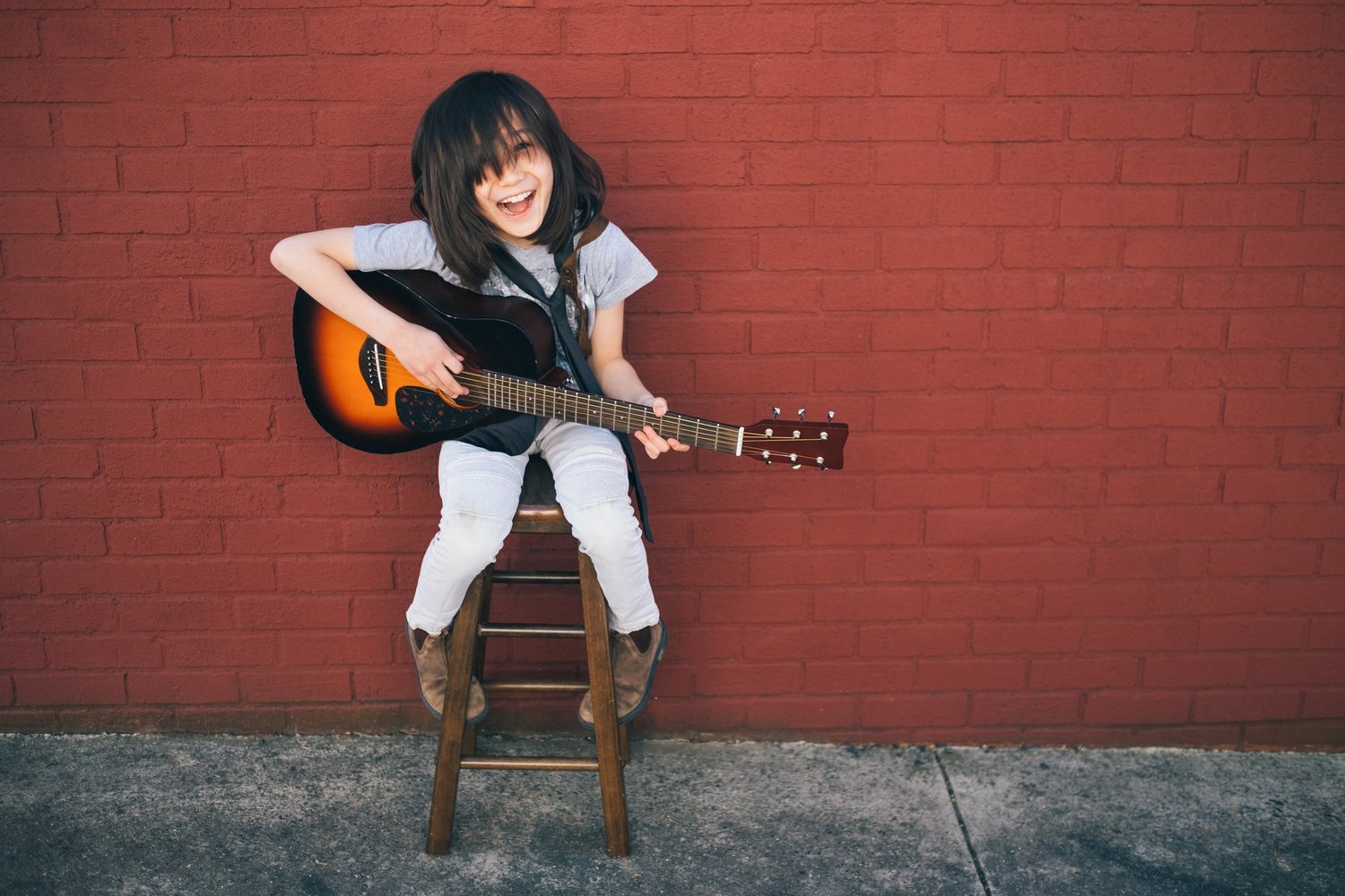 Child laughing and playing an acoustic guitar